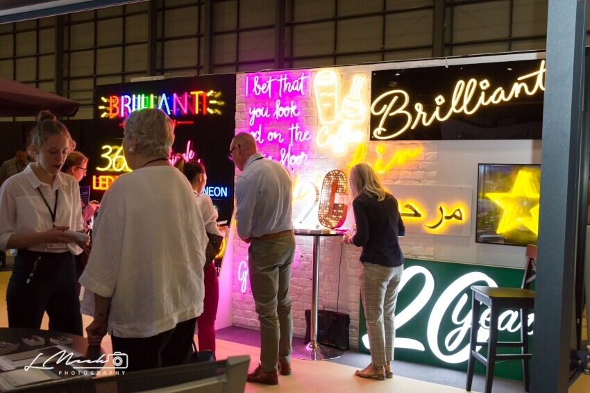 Attendees viewing neon signage at the Hotel & Resort Innovation Expo.