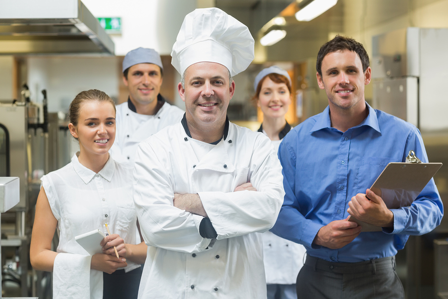 Head chef posing with the team behind him in a professional kitc