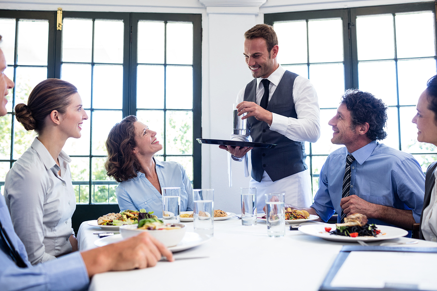 Waiter serving water to the business people in restaurant