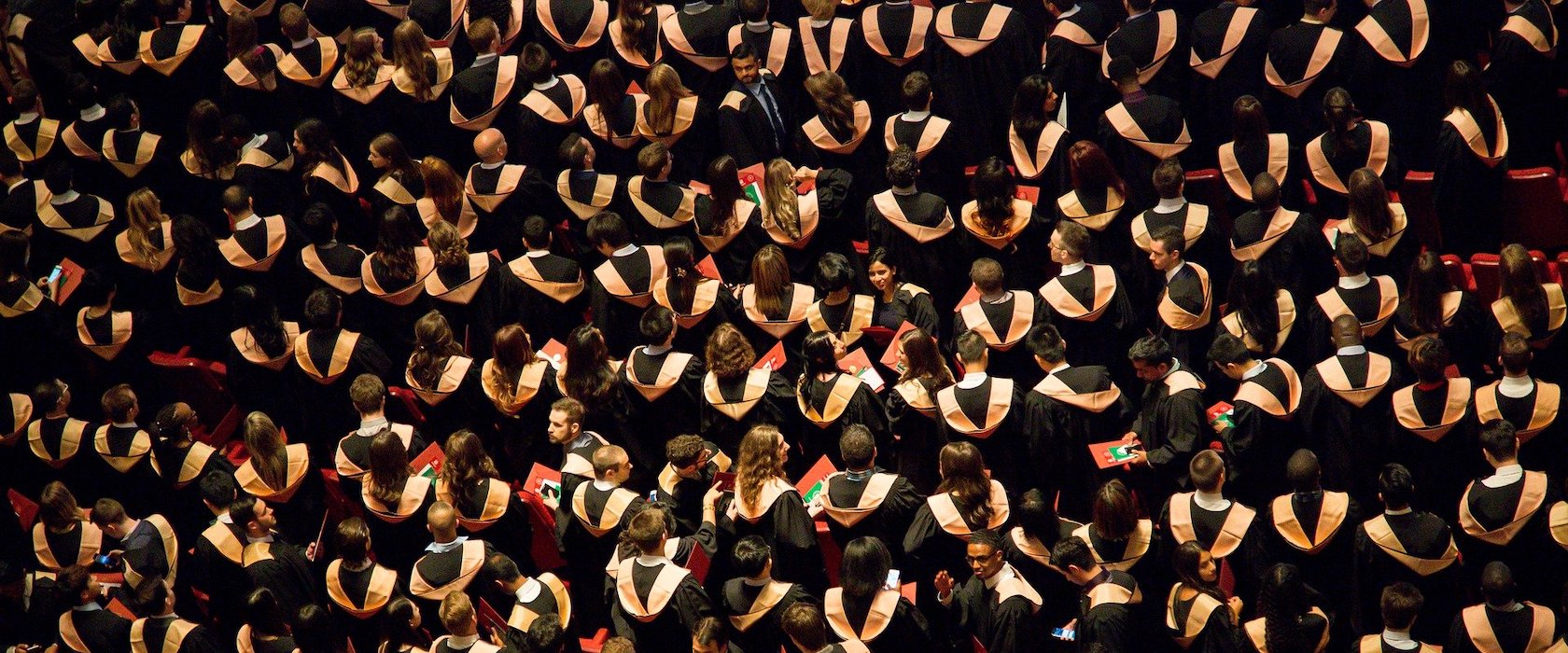 An overhead view of a large group of students in graduation gowns at a ceremony
